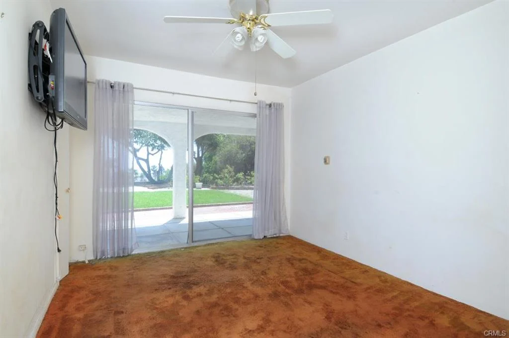 Room with ceiling fan, TV, sliding door, carpet, and walls