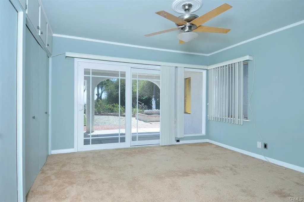 Room with blue walls, ceiling fan, carpet, and sliding door