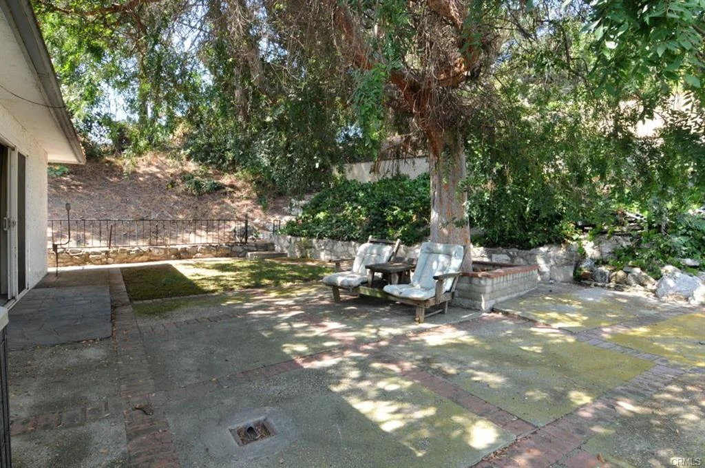 Patio with chairs, tree, plants, and stone wall