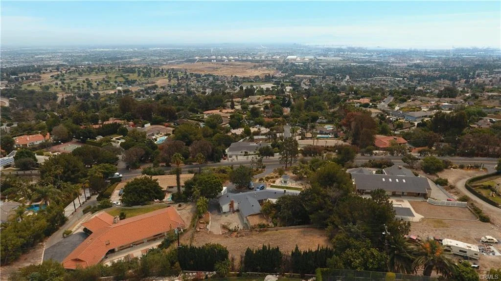 Aerial view of house in California real estate with driveway, trees, and nearby homes