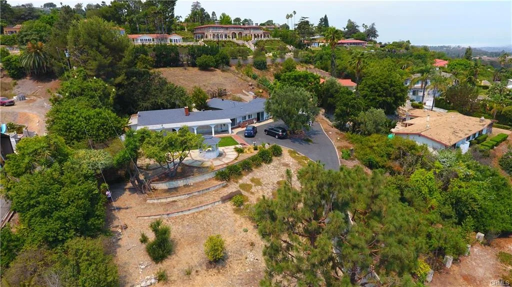 Aerial view of house in California real estate with driveway, trees, and nearby homes