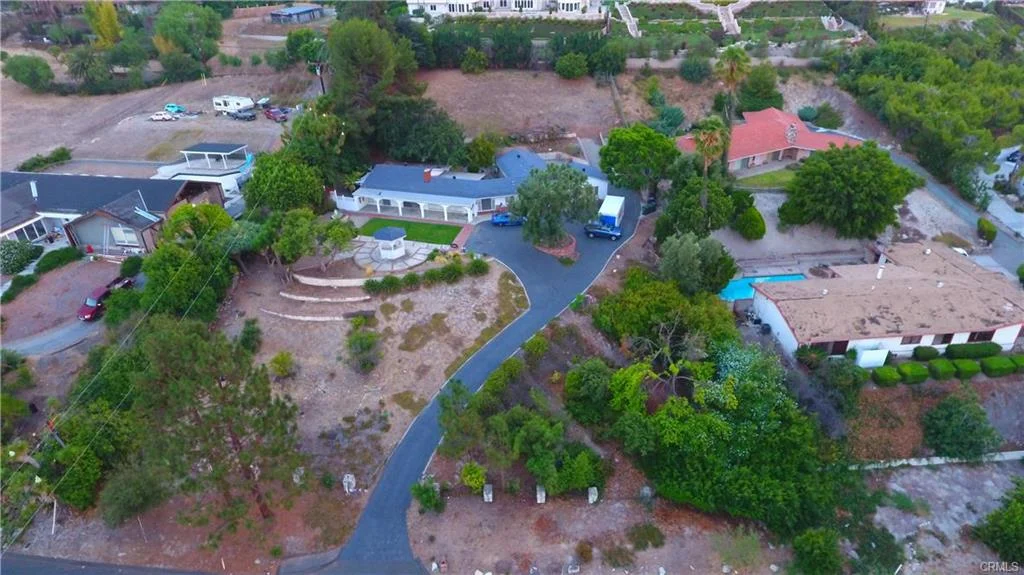 Aerial view of neighborhood with houses, yards, roads, and trees in California real estate