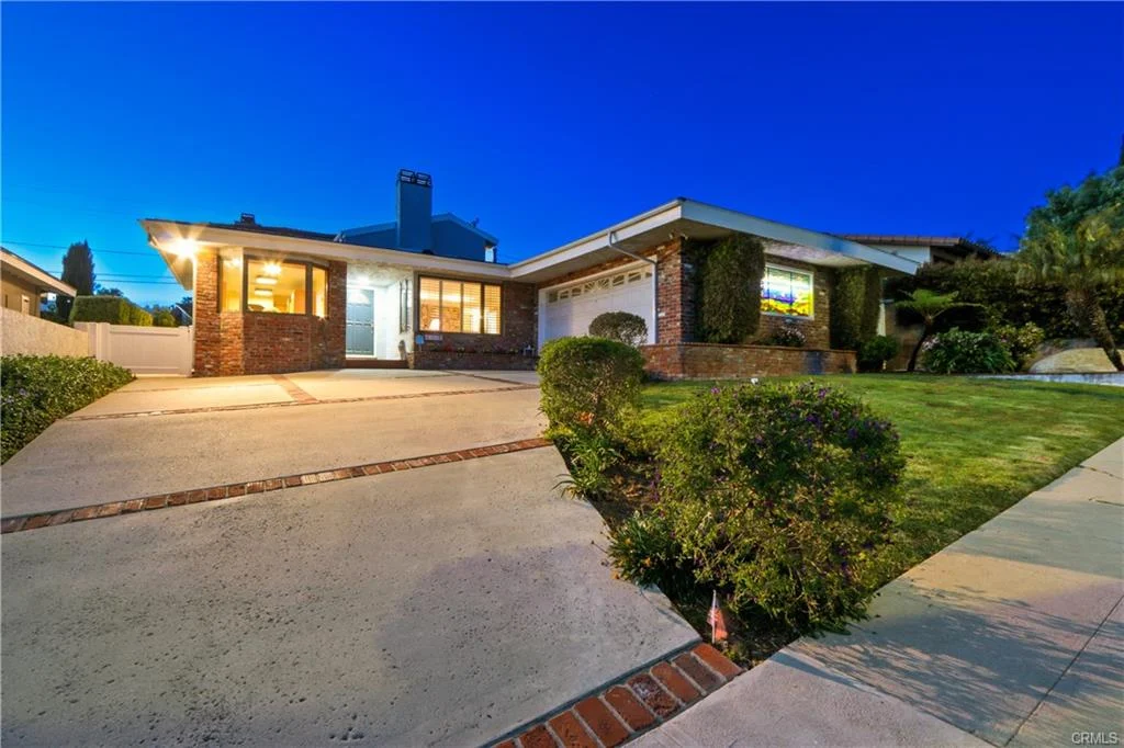 Single-story house with brick exterior, windows, and lawn, California real estate.
