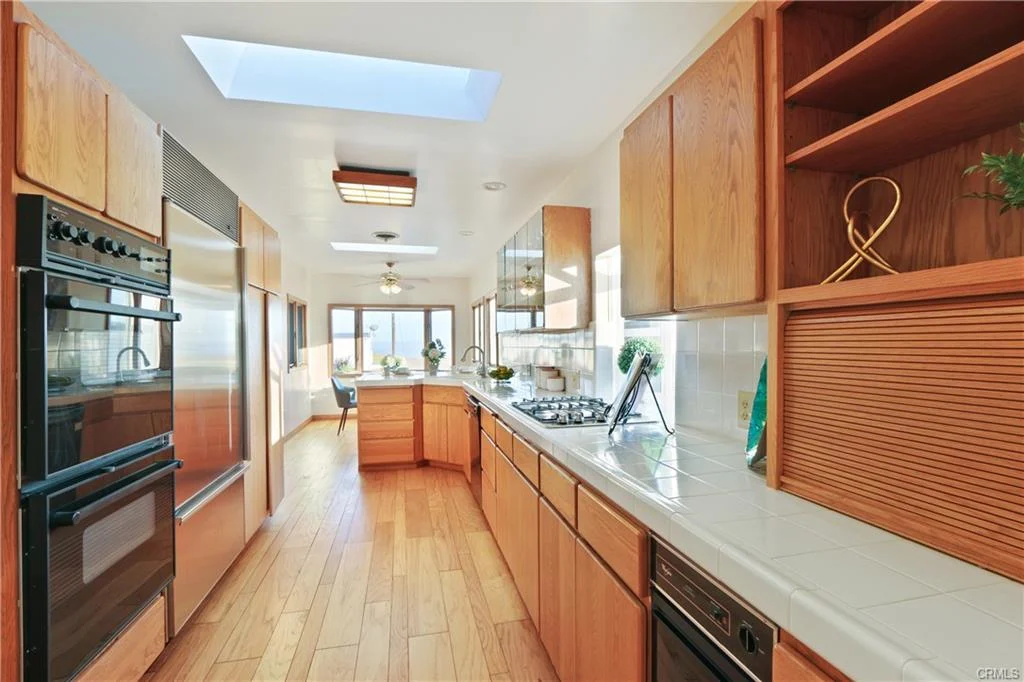 Kitchen with wooden cabinets, windows, stove, and island.