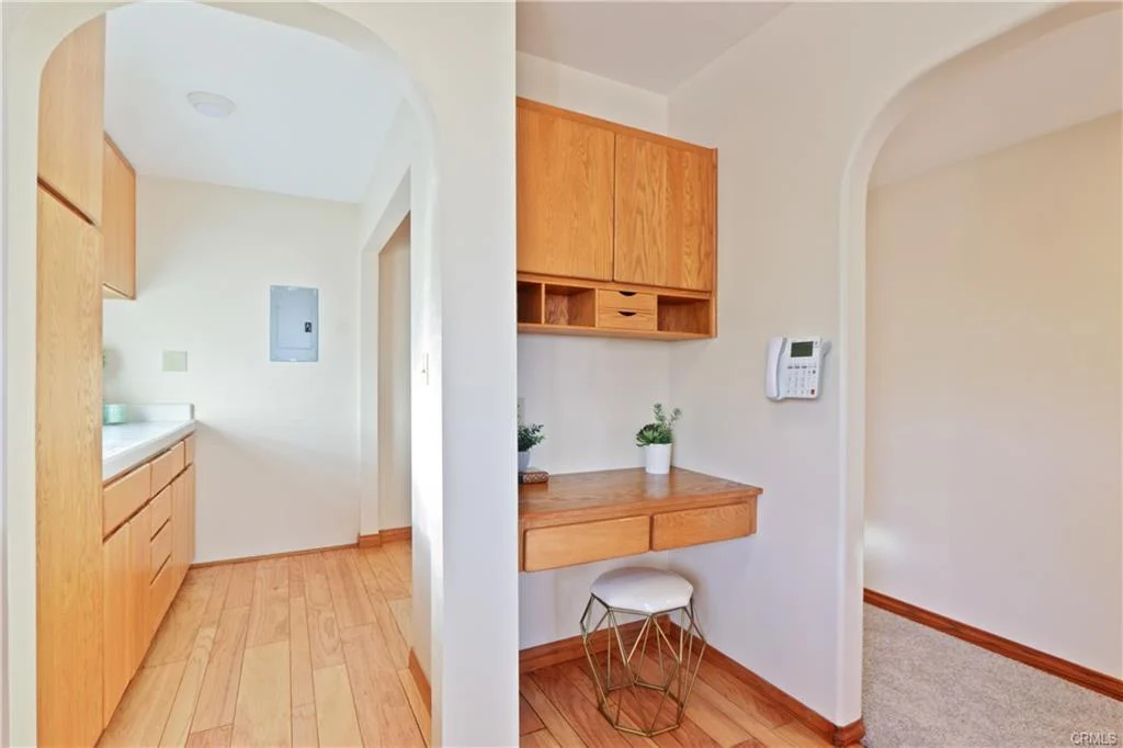 Room with wooden desk, stool, and light walls.