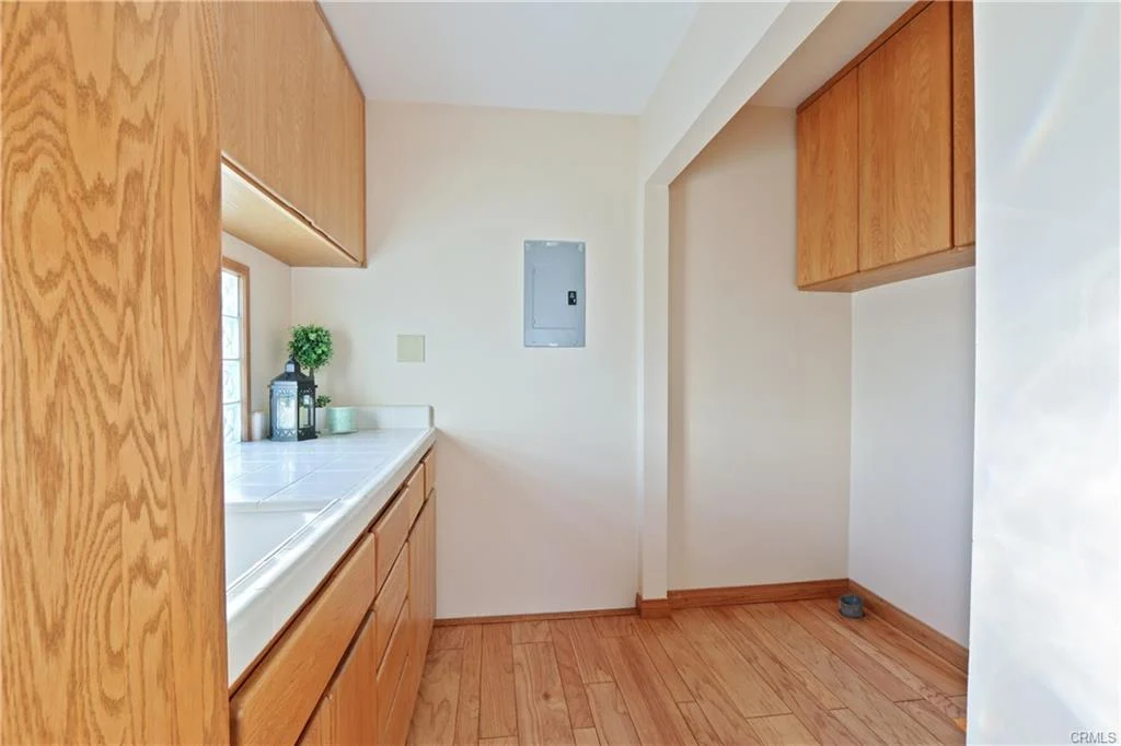 Kitchen with wooden cabinets, white countertop, window, and hardwood floor.