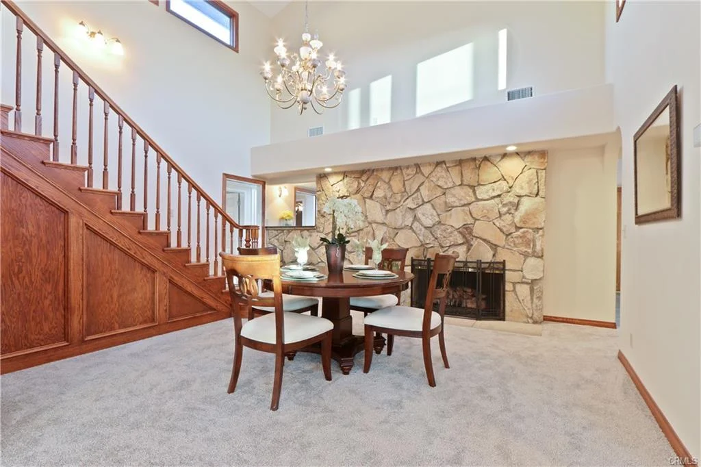 Dining area with round table, chairs, fireplace, and staircase.