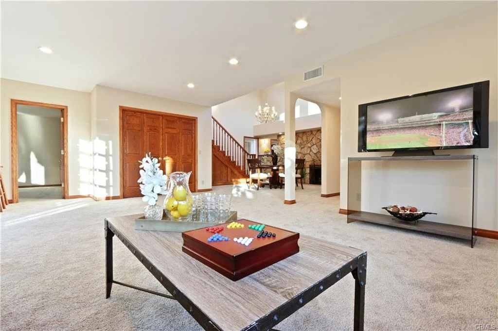 Living room with coffee table, TV, staircase, and windows.
