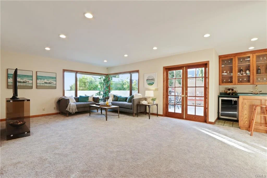 Living room with gray sofas, carpet, windows, and bar area.