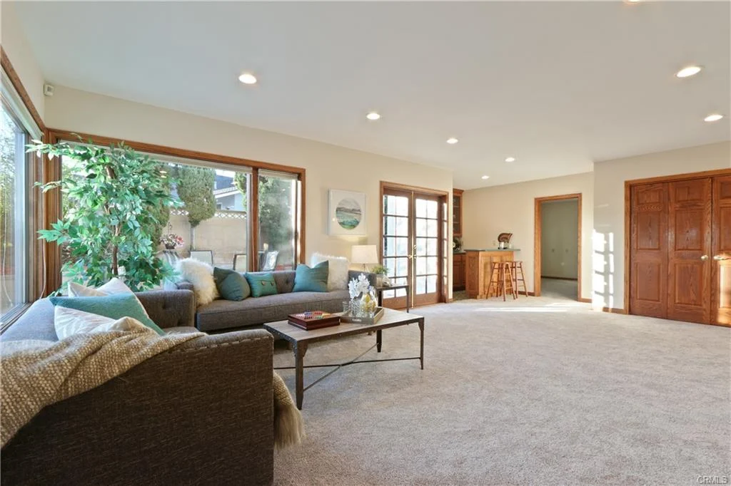 Living room with sofa, coffee table, windows, and bar area.