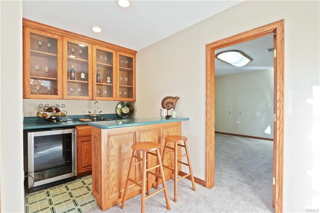 Bar area with green countertop, wooden cabinets, and stools.