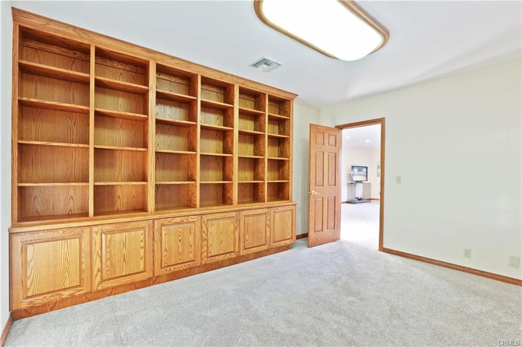 Room with carpet, built-in wooden bookshelf, and door.