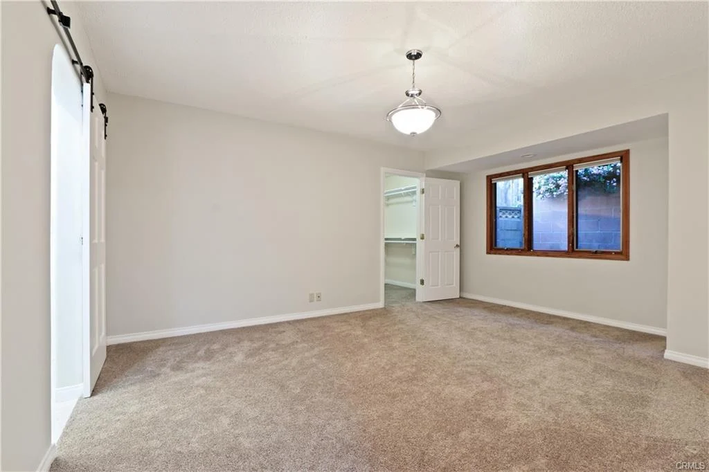 Room with beige carpet, ceiling light, large window, and open door.