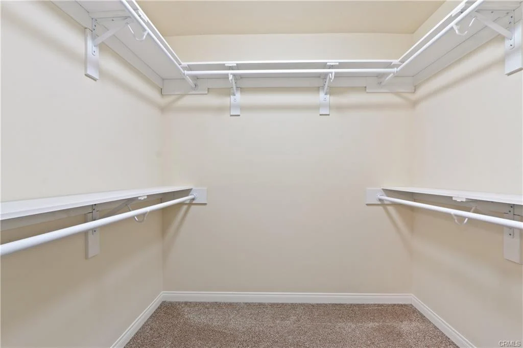 Closet with white shelves and neutral walls.