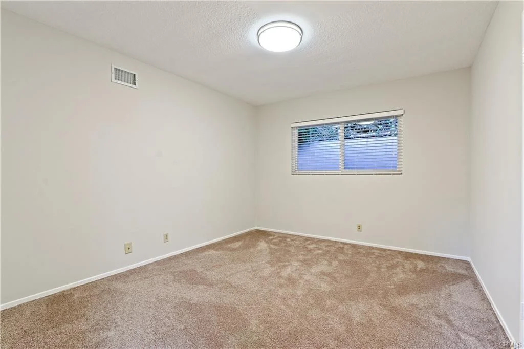 Room with beige carpet, white walls, and window.