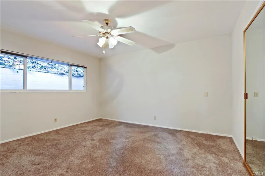 Room with carpet, ceiling fan, and windows.