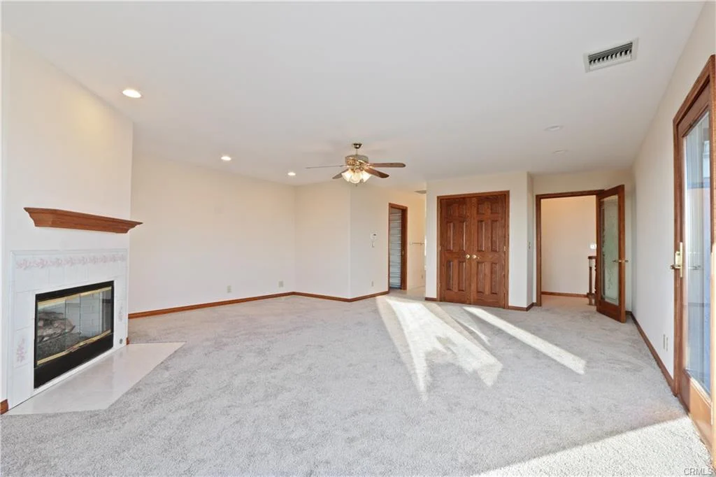 Living room with ceiling fan, carpet, and fireplace.