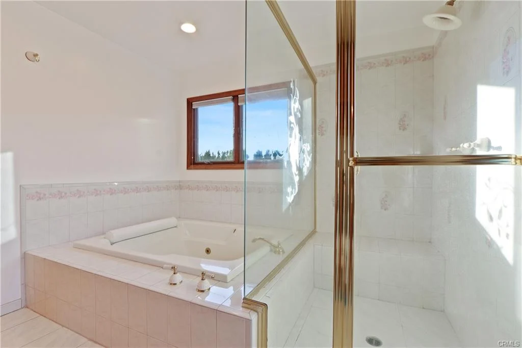 Bathroom with glass shower, jetted tub, and windows.
