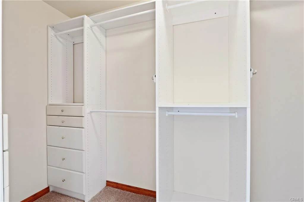 Empty white closet with drawers and shelves.