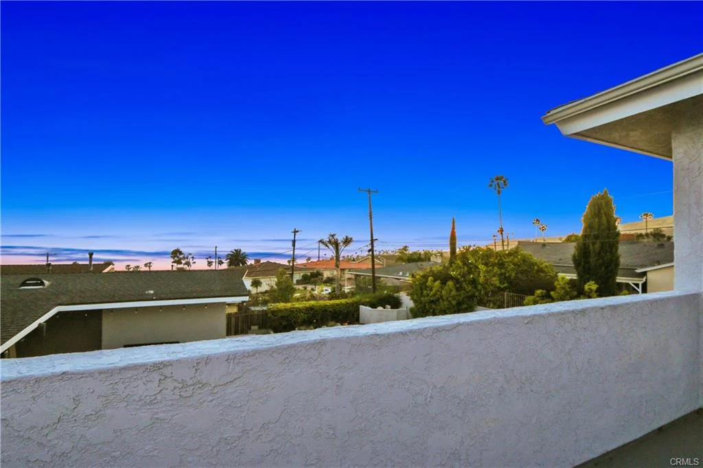 Balcony with view of rooftops and palm trees.