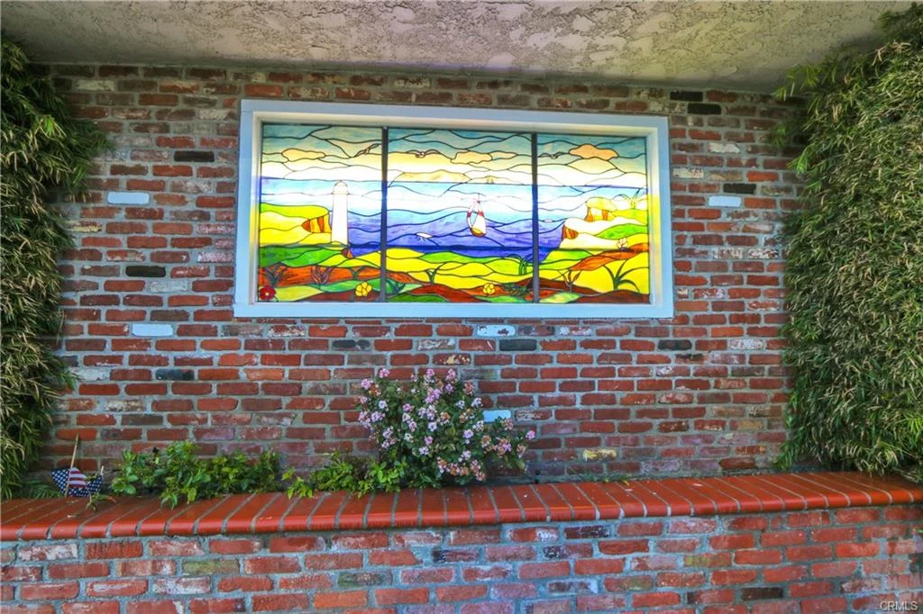 Stained glass window with landscape, mountains, water, and trees.