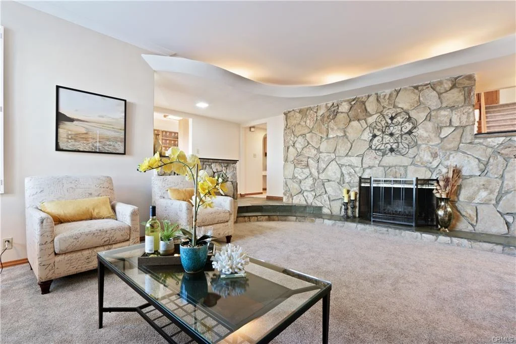 Living room with chairs, coffee table, and stone fireplace.
