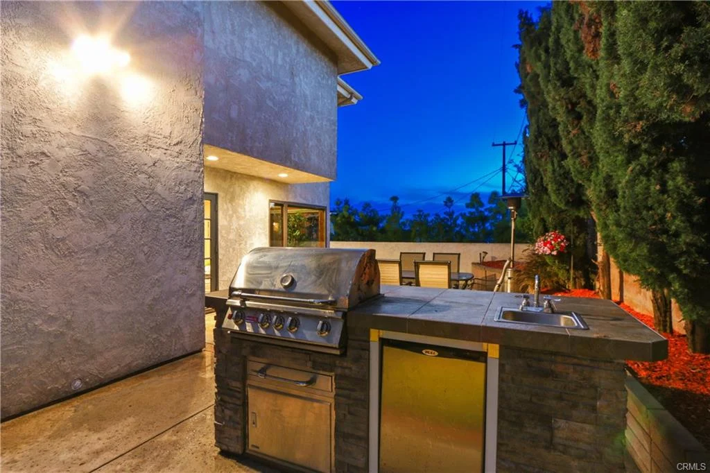 Backyard with outdoor kitchen, grill, patio furniture, and plants