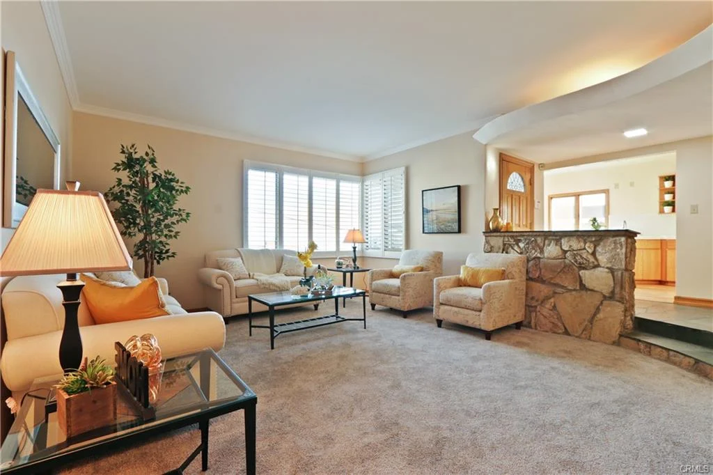 Living room with beige couch, armchairs, coffee table, and plants.