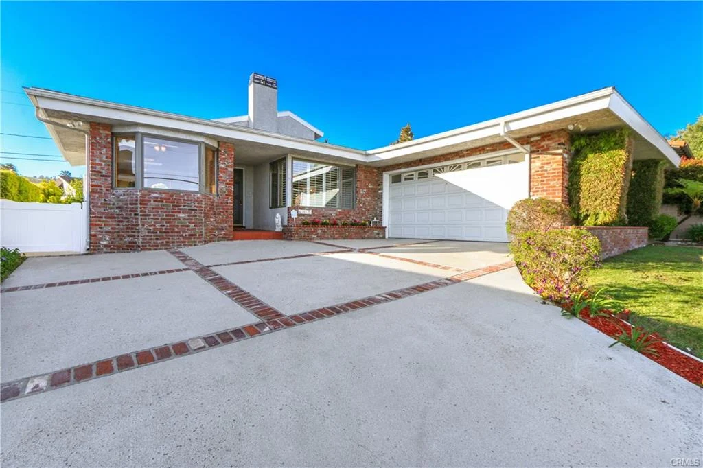 Front view of a house with brick facade, garage, and plants, California real estate.