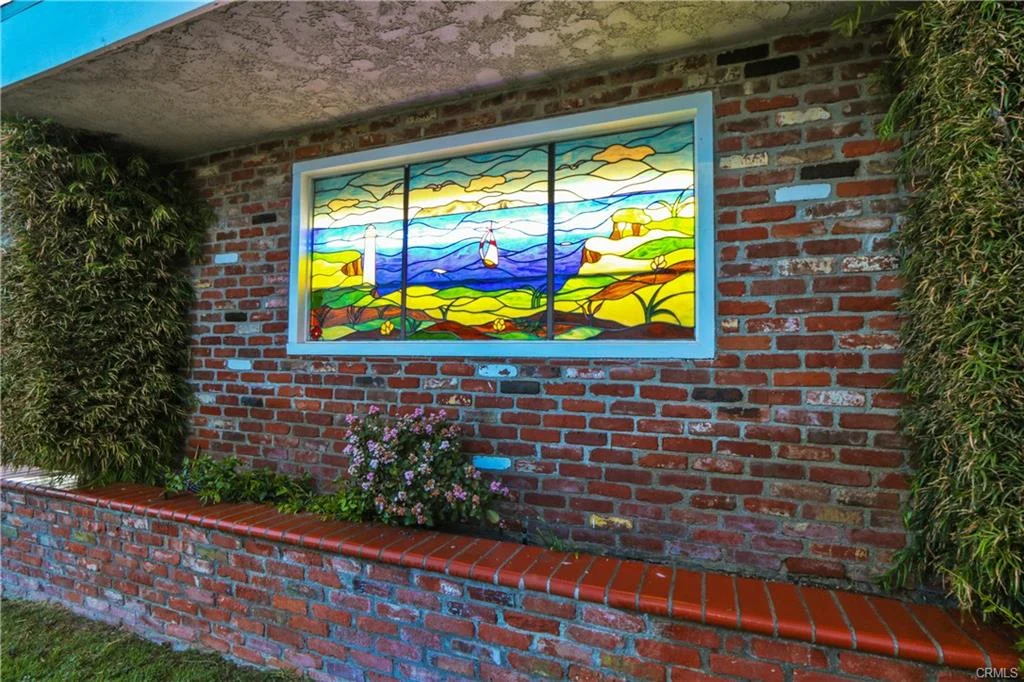 Stained glass window with coastal landscape and lighthouse.