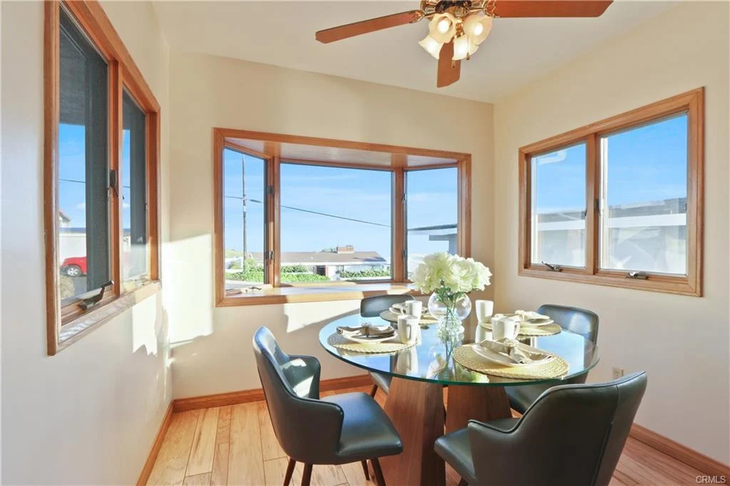 Dining area with round glass table, black chairs, and windows