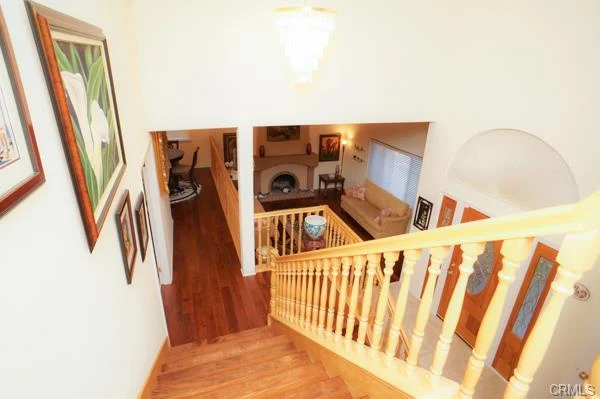 A view from the top of a staircase looking down into a foyer or living area with various artworks on the walls.