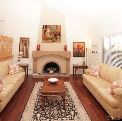 Living room with two beige sofas, a wooden coffee table, a stone fireplace, and a decorative rug on a wood floor.