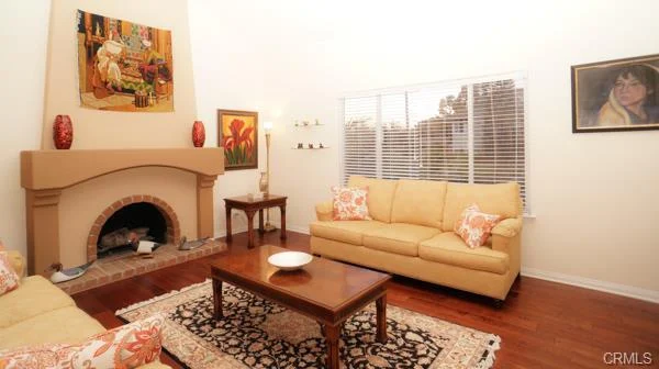 Living room with a beige couch, a wooden coffee table, a fireplace, and artwork on the walls.