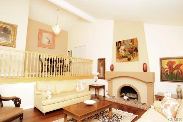 Living room with a high ceiling, a beige couch, a coffee table, a fireplace, and an upstairs balcony.
