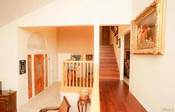 Hallway with wood floors, a staircase, and two doors.
