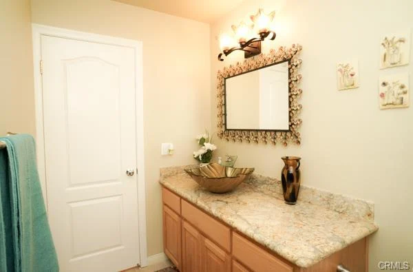 Bathroom with wood cabinets, a mirror, and a towel.