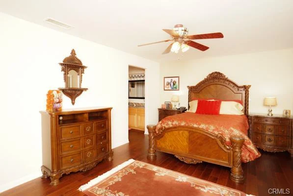 Bedroom with a wood bed, dresser, and wood floor.