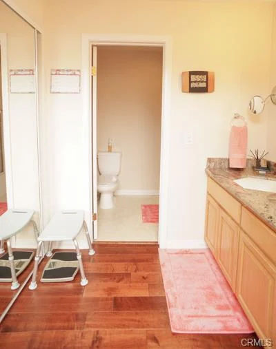 Bathroom with a wood floor, double mirror, and pink mat.