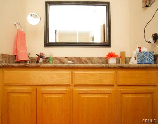 Bathroom with wood cabinets, a mirror, and a towel.
