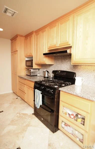 Kitchen with wood cabinets, a black stove, and tile floor.