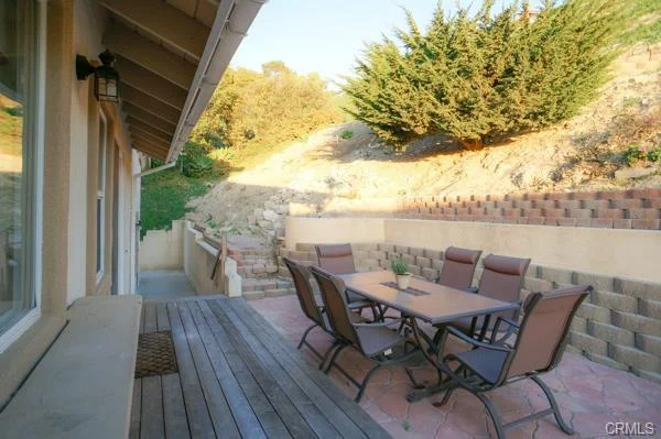 California real estate house, a patio with a table, chairs, and a yard on a hill.