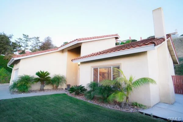 California real estate house, a sloped roof, a yard with palm trees, and grass.