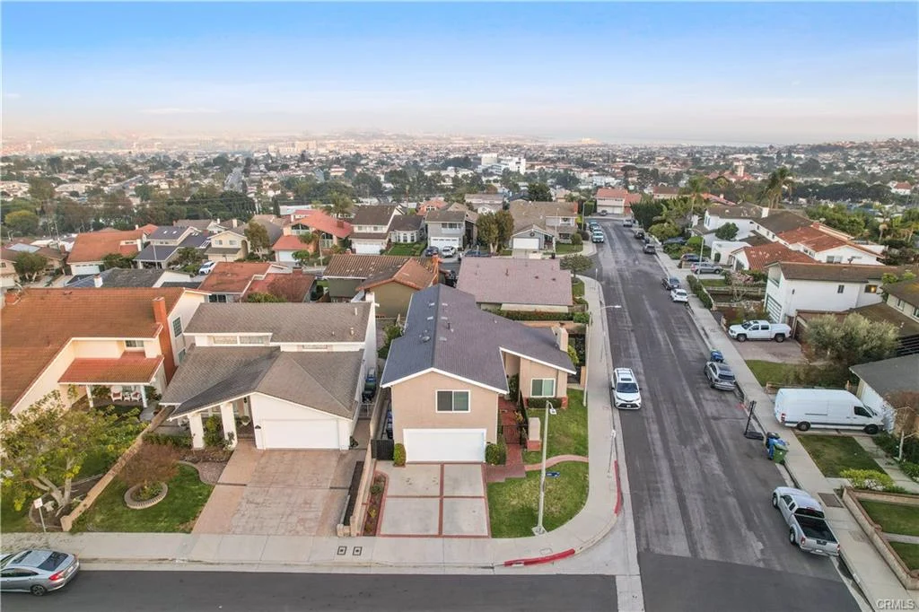 Aerial view of many houses California real estate with trees and cars on the street.