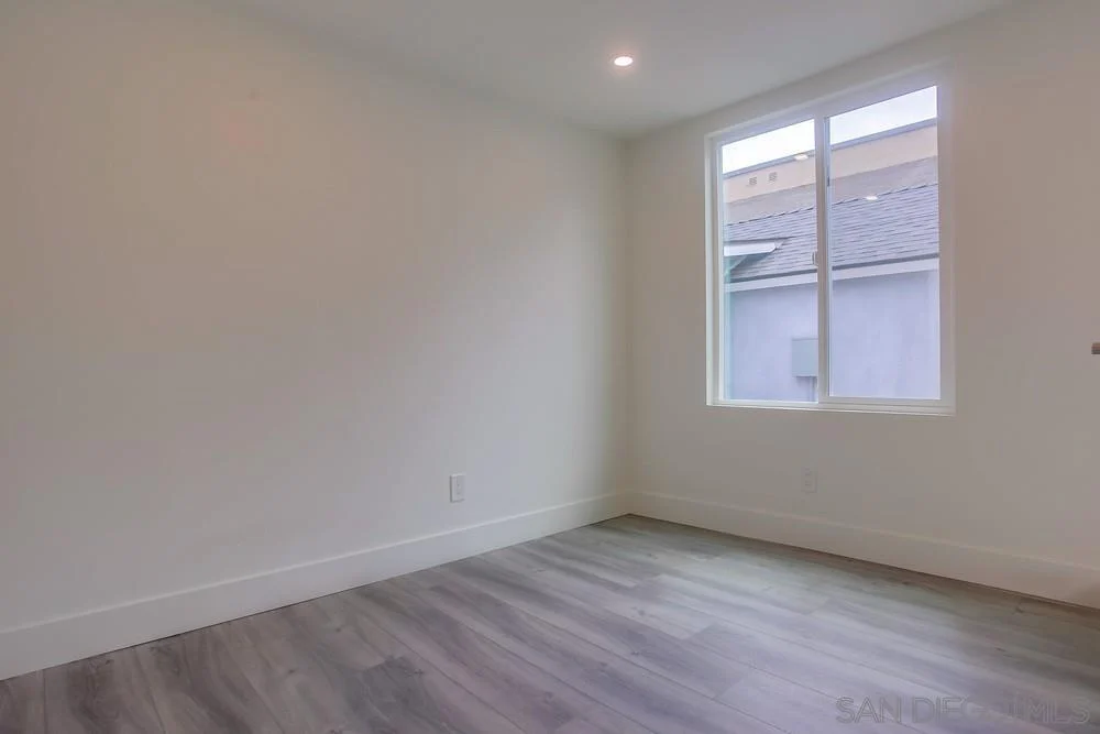 Room with light walls, window, and gray floor.