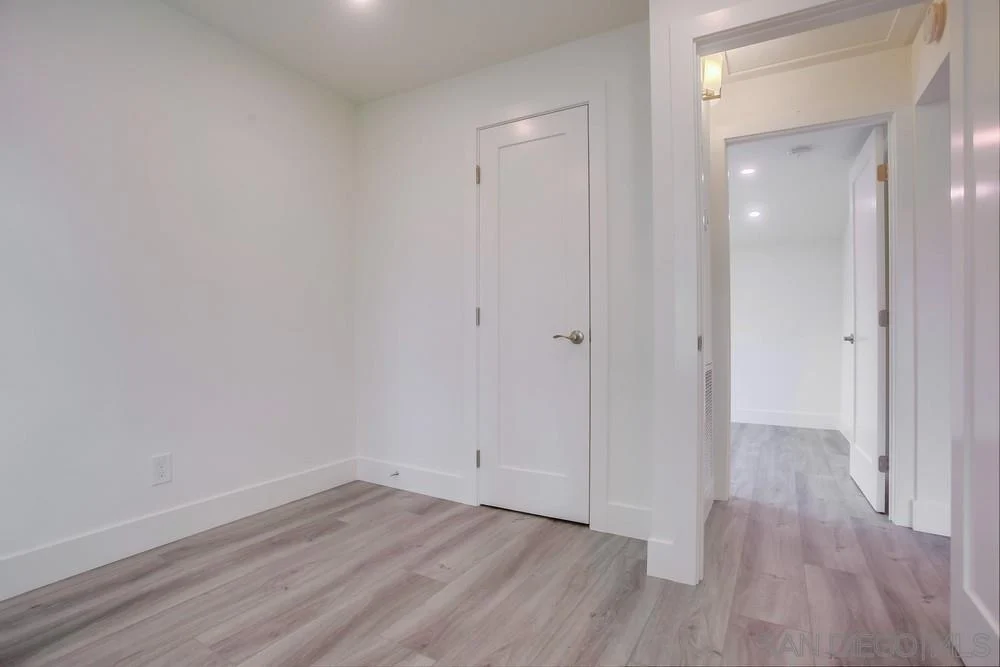 Room with white walls, door, and light wood-like floor.