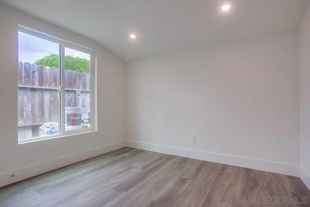 Room with large window, light walls, and light floor.