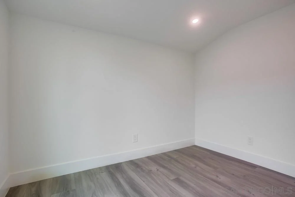Room with light walls, hardwood floor, and ceiling light.