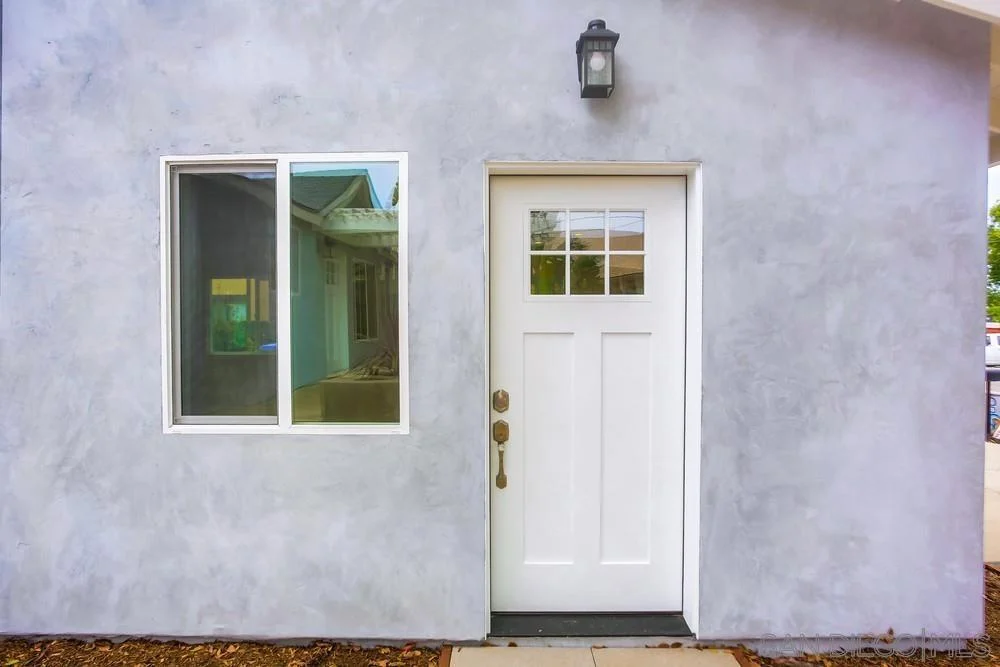 Wall with light gray paint, white door with glass panes, and large window.