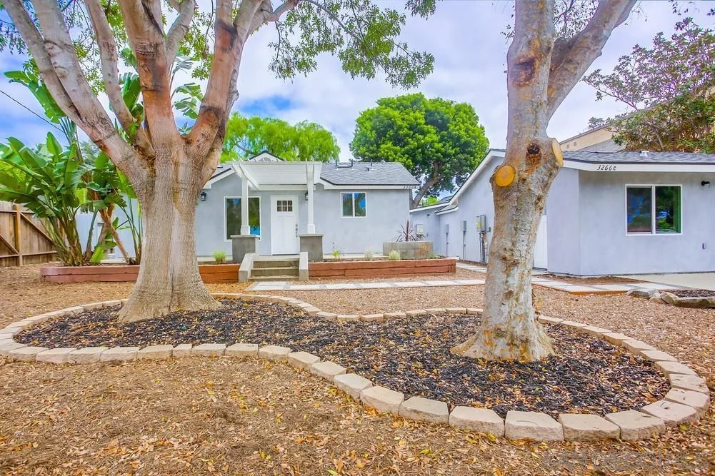 California real estate house with backyard, two trees, walkway, and garden areas.
